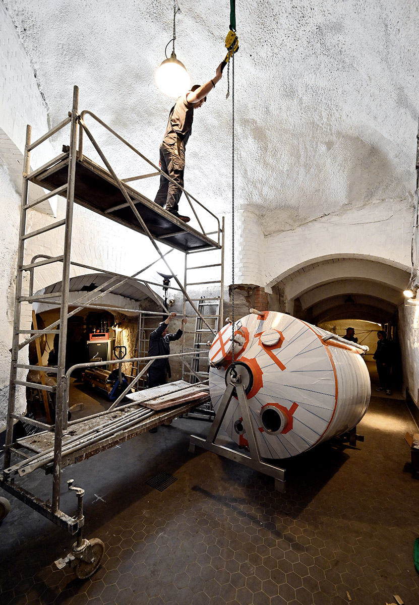 Mit Hilfe eines in die Felsendecke geschraubten Hakens wird der Läuterbottich aufgerichtet und in Postion gebracht.