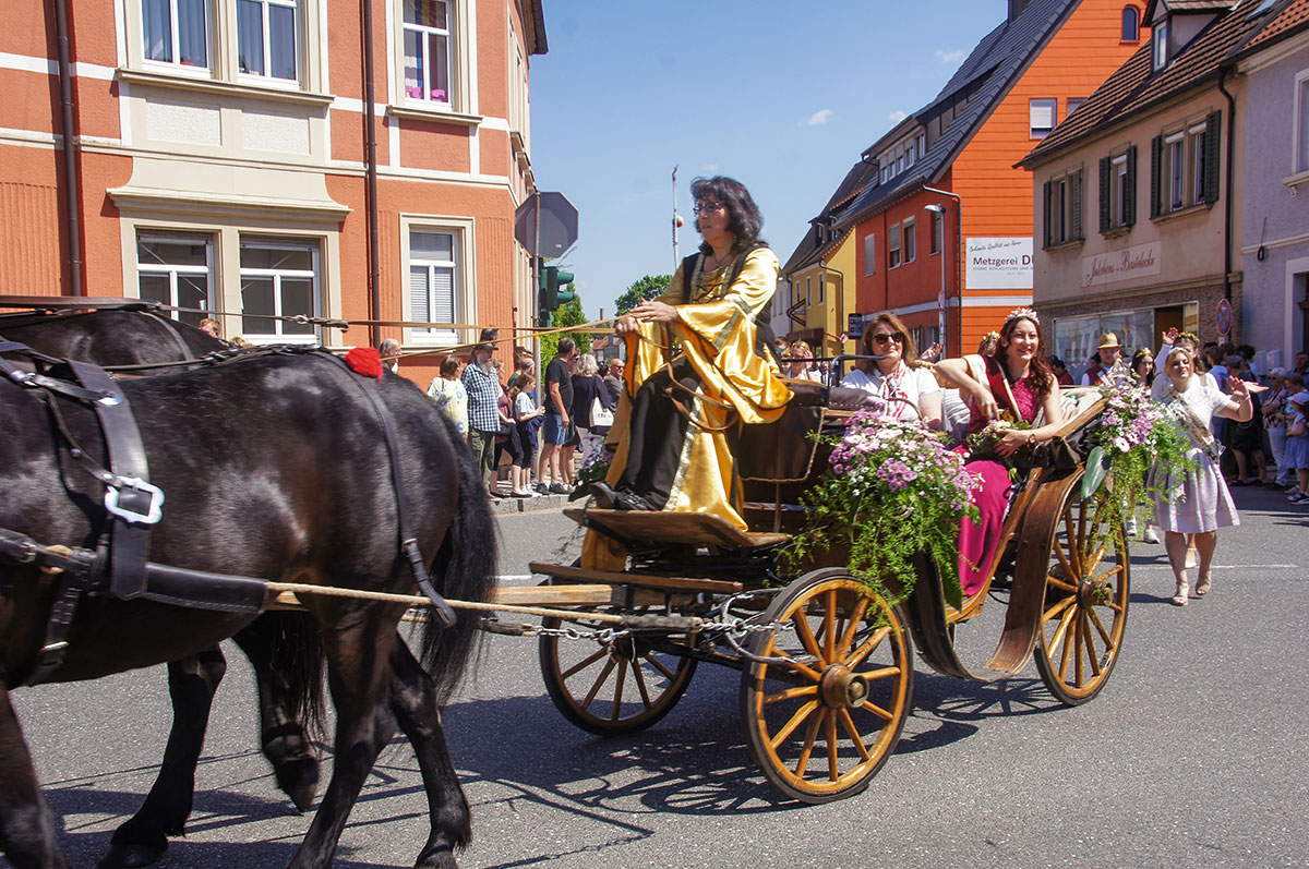 Ein strahlendes Lächeln und süße Kleinigkeiten fürs Volk – die frisch gekrönte Maienkönigin Julia Anwander und die stellvertretende Regierungs­vizepräsidentin Birgit Riesner führen den Festzug an.